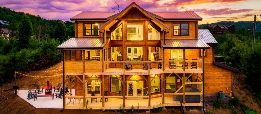 Exterior of a large group cabin with luxury amenities at twilight, with colorful sunset hues.