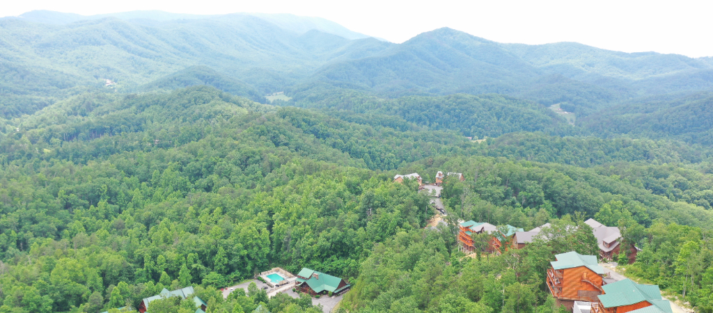 Aerial of Smoky Mountains with Cabins Aerial view of the Great Smoky Mountains with log cabins in the foreground on a mildly bright day.
