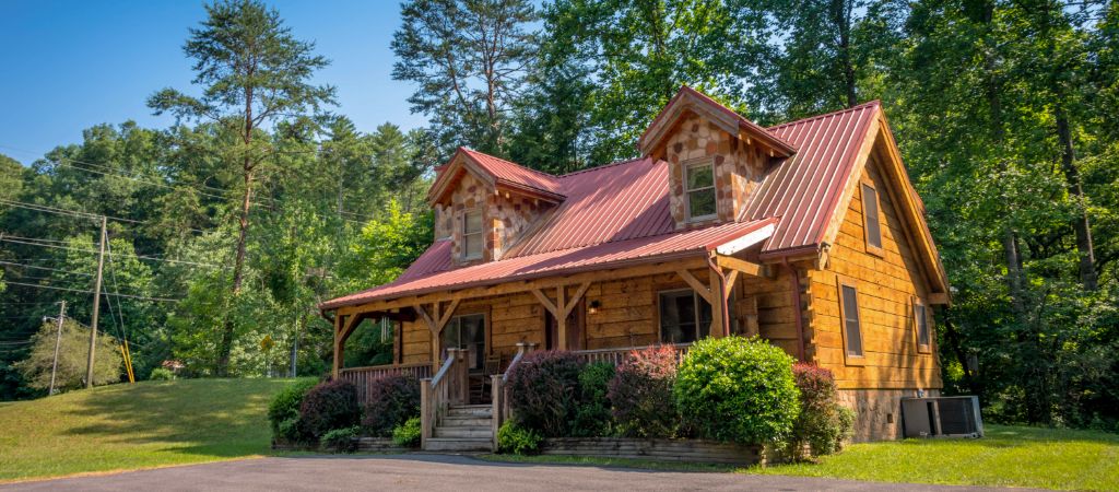 Cabin with red roof surrounded by trees.
