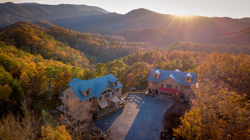 Fall Lodges Smoky Mountains Two Smoky Mountain lodges sit on a hillside, with colorful fall leaves painting the mountain view backdrop.