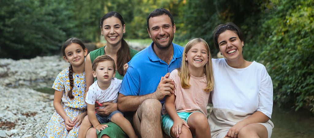 Family Portrait by a Stream A young family smile while sitting on the bank of a mountain stream in a family portrait.