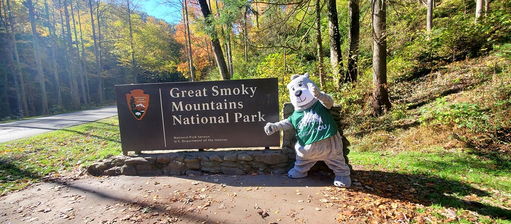 Sign that reads Great Smoky Mountains National Park , with Barry the Bear, the mascot for Cabins for YOU.