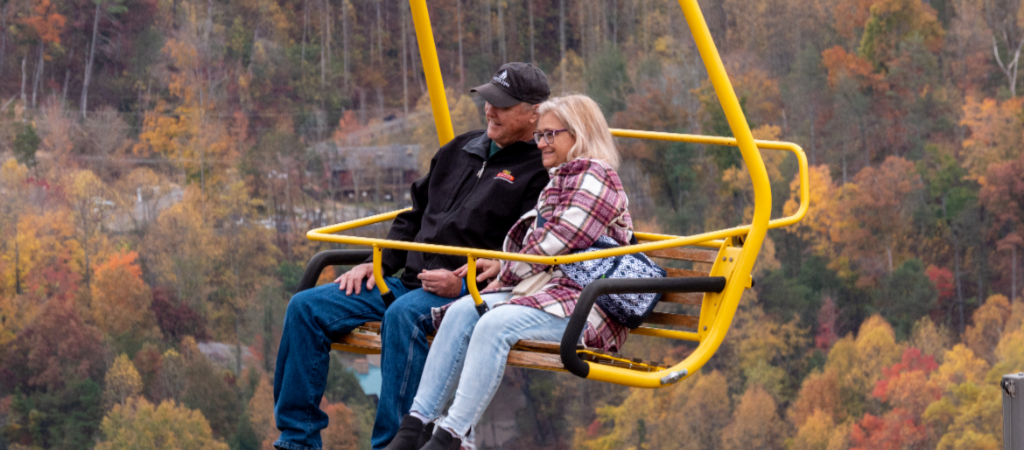 Senior Couple Ridge the Gatlinburg SkyLift A smiling senior couple lean onto each other while riding the Gatlinburg SkyLift above colorful trees in fall.
