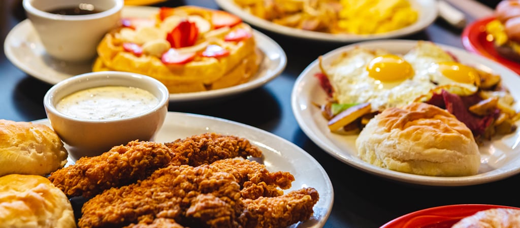 Southern Comfort Breakfast Food An overhead shot of a table with Southern comfort food for breakfast, like fried chicken, buttered biscuits, and fluffy waffles.