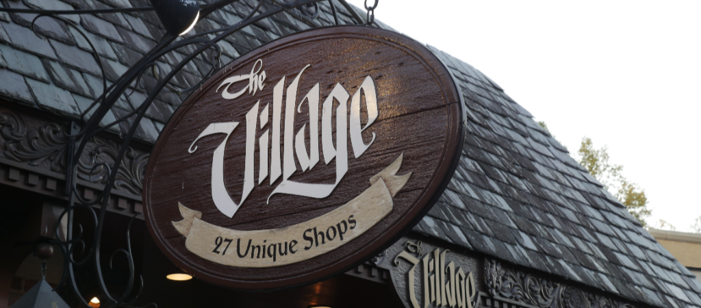 The Village Shops Hanging Sign in Gatlinburg A vintage-style hanging sign reads The Village 27 Unique Shops in downtown Gatlinburg.